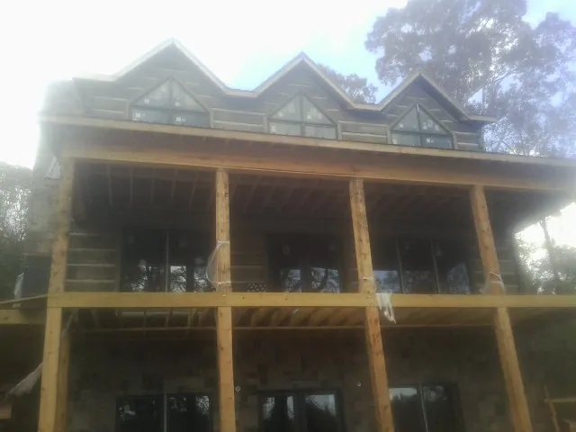 Dormers and porch framing on a large log home under construction — Roof Coating work by our crew in Vail