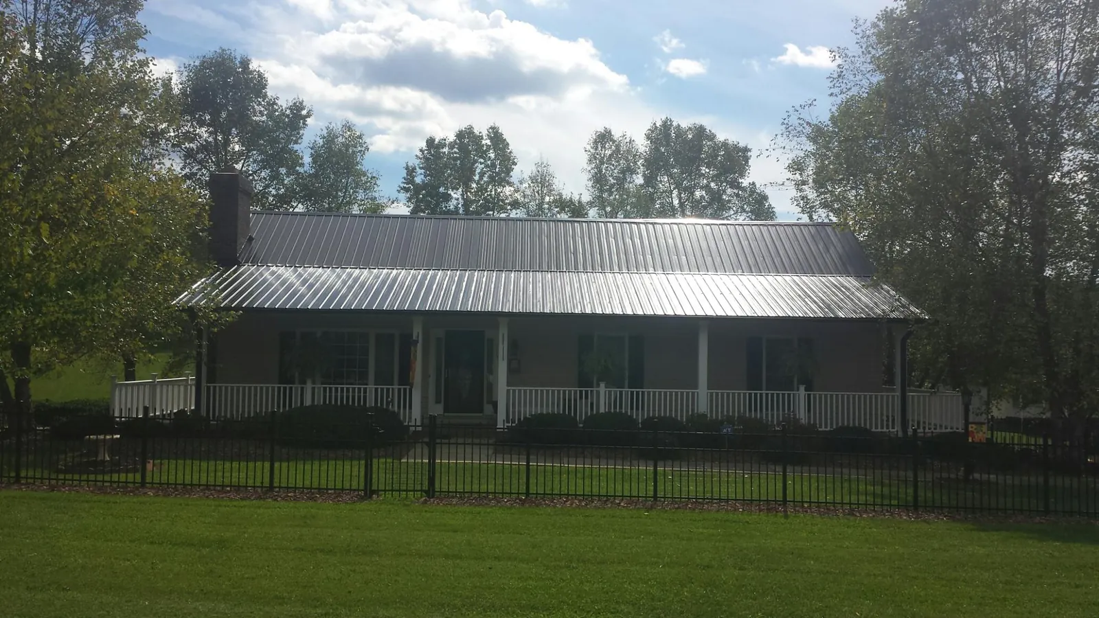 Gray metal roof on a brick ranch with a full width front porch — Gutter Guard Installation work by our crew in Vail